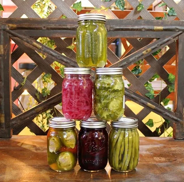 A pyramid of pickled jars on a wooden counter